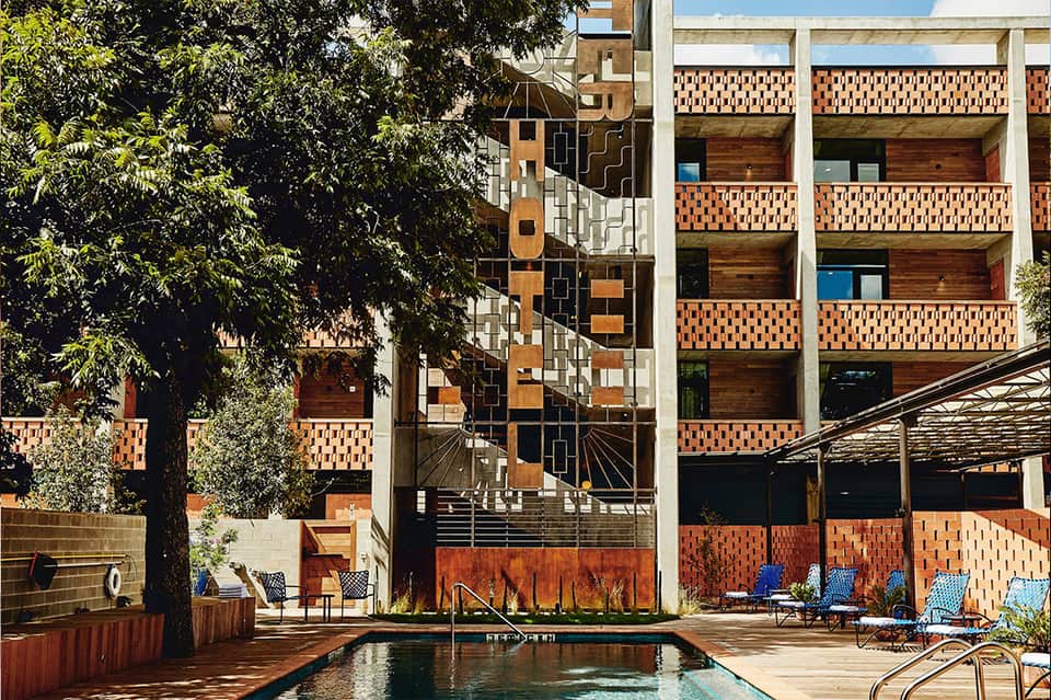 Urban resort pool surrounded by modern brick and concrete architecture with lounge chairs