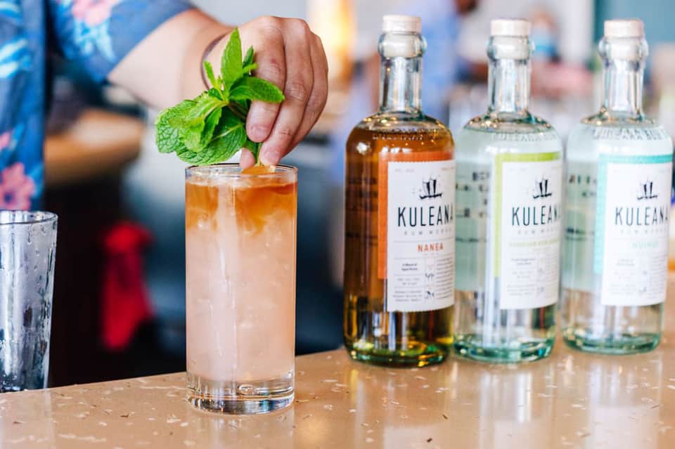 Bartender preparing cocktail with mint garnish, Kulean spirit bottles displayed on counter at resort bar