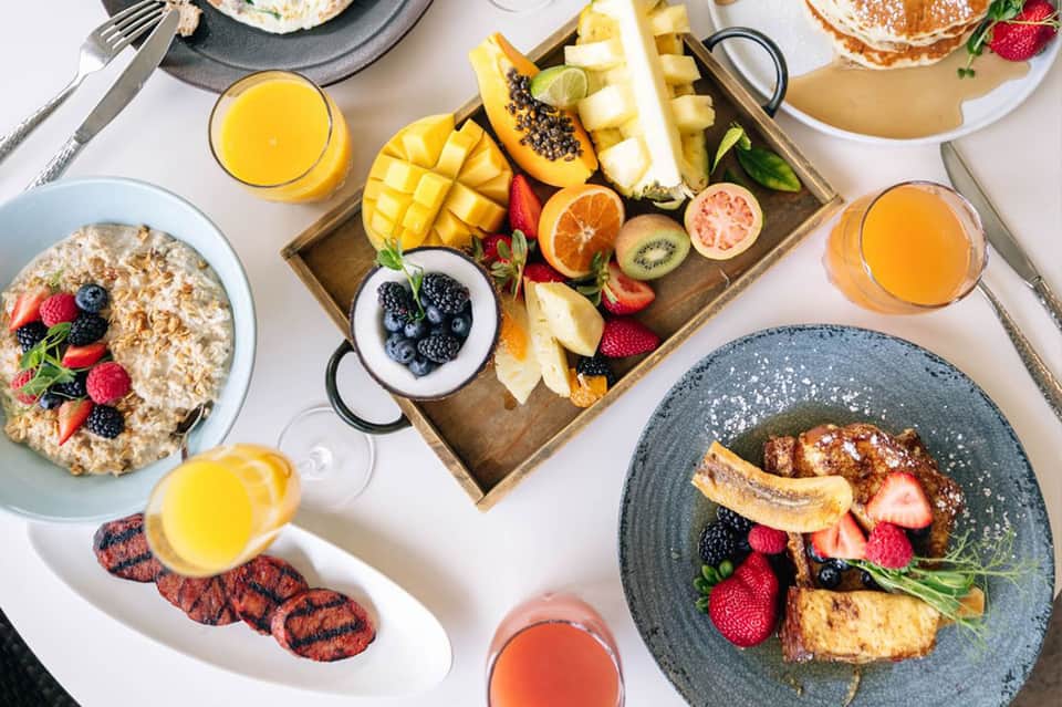 Breakfast spread with oatmeal, fresh fruit platter, pastries, juice, and coffee service