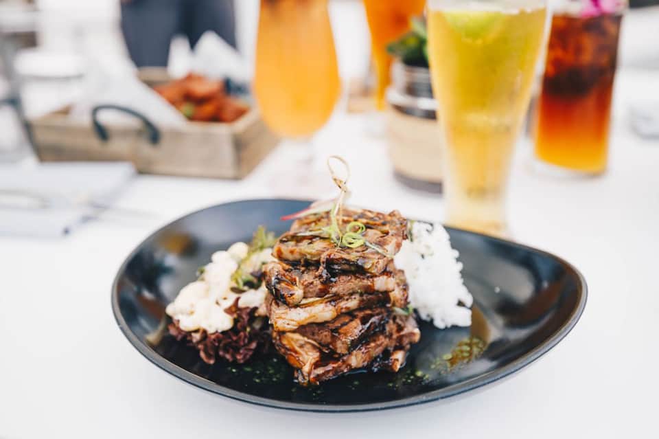 Gourmet plated steak dish with garnishes and beverage glasses at upscale restaurant
