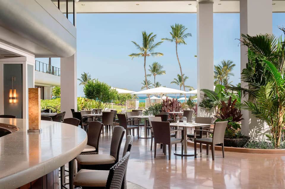 Upscale resort dining area with ocean and palm tree views through large windows