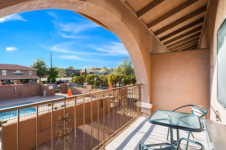 Balcony overlooking resort pool and grounds with railing and patio furniture