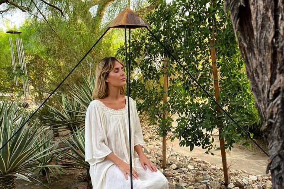 Woman in white dress relaxing under umbrella in tropical garden setting