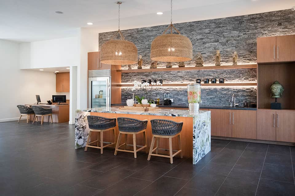 Modern resort kitchen with wood cabinetry, stone backsplash, and bar seating