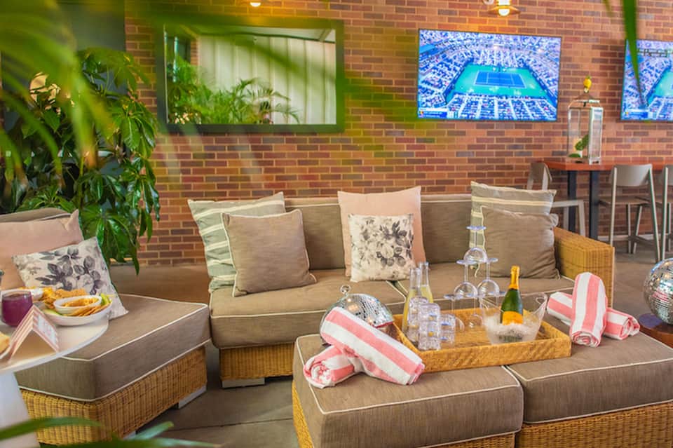 Hotel lounge with brick walls, comfortable seating, and TV screens displaying amenities