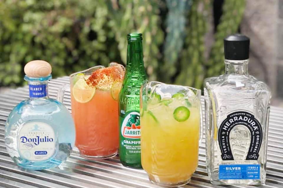 Tequila cocktails and spirits displayed on an outdoor table with succulent plants in background