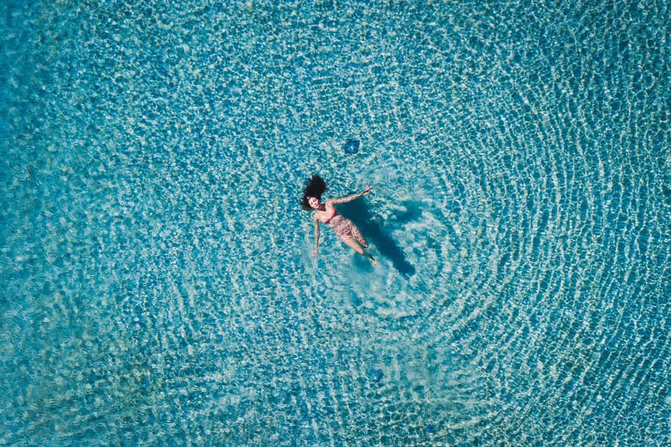 Aerial view of person swimming in crystal clear turquoise pool water