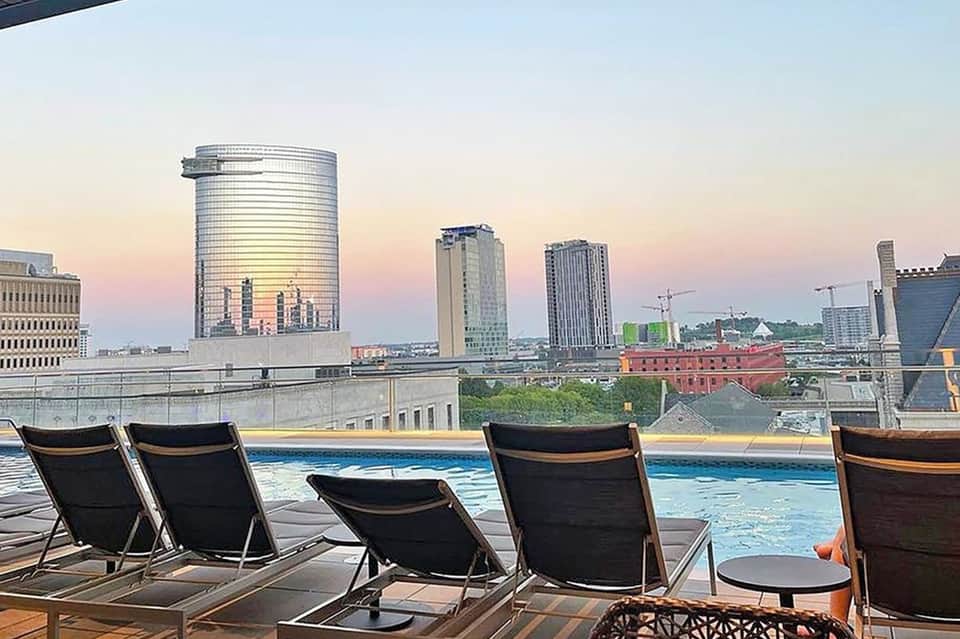 Rooftop pool deck with lounge chairs and city skyline at dusk