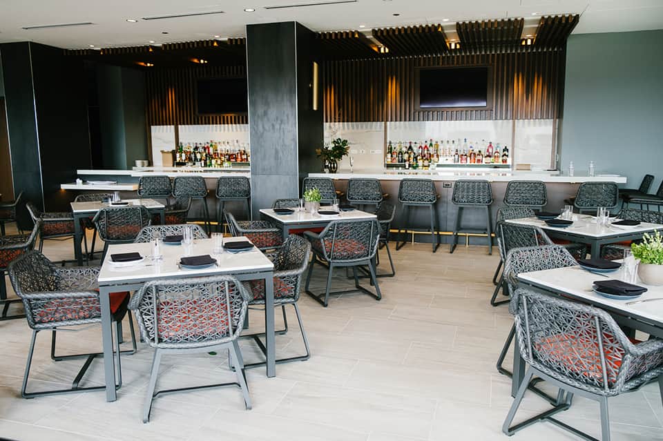 Modern hotel restaurant and bar interior with patterned chairs and full bar setup