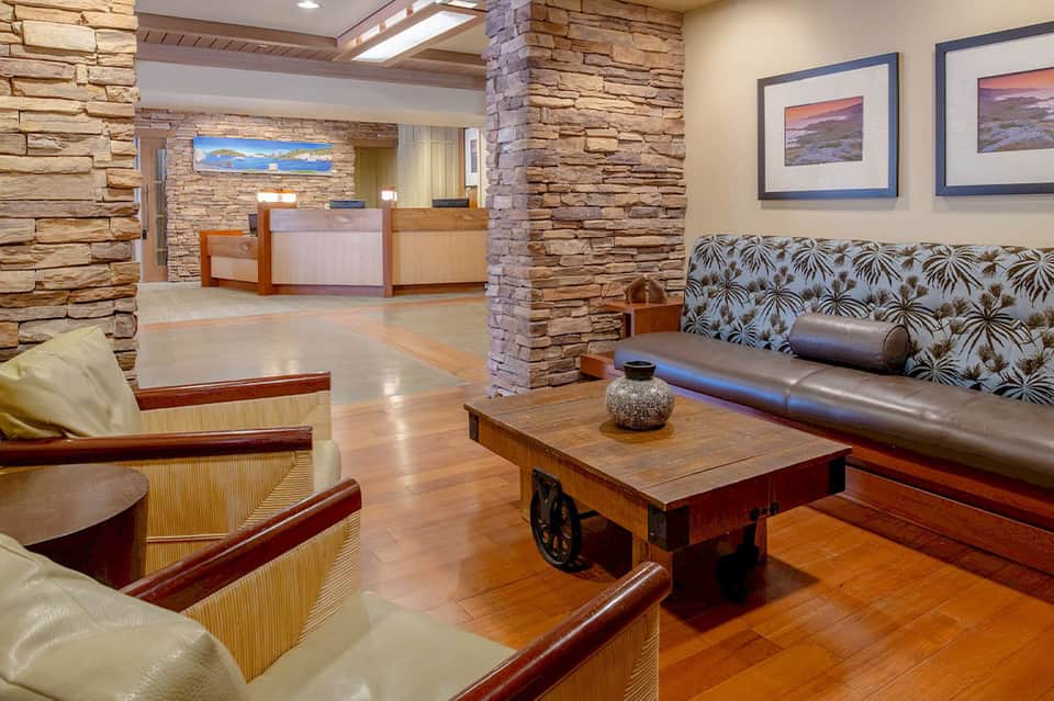 Hotel lobby with stone accent walls, comfortable seating, wooden furnishings, and check-in desk