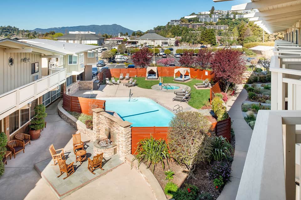 Mid-century modern resort pool with light blue water, orange accents, and mountain views