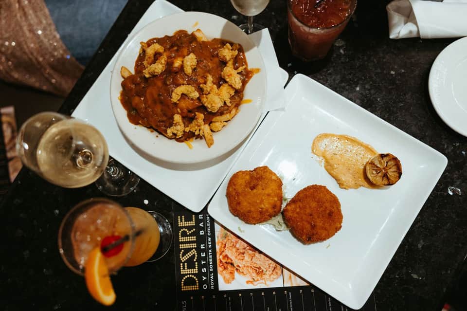 Gourmet dinner plates with fried calamari and seared fish beside cocktails in upscale restaurant setting