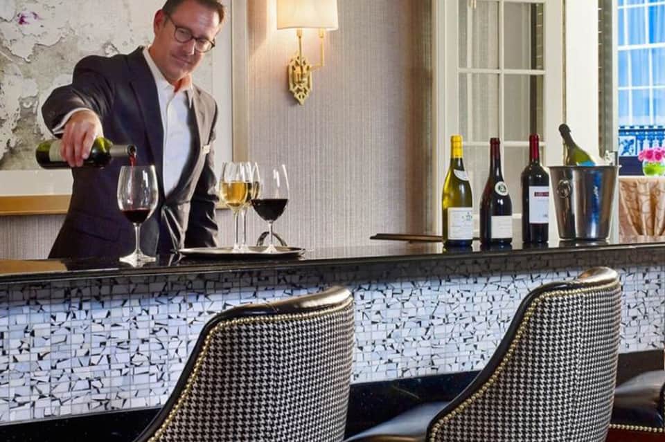 Bartender pouring wine at an upscale bar with houndstooth pattern and elegant interior design