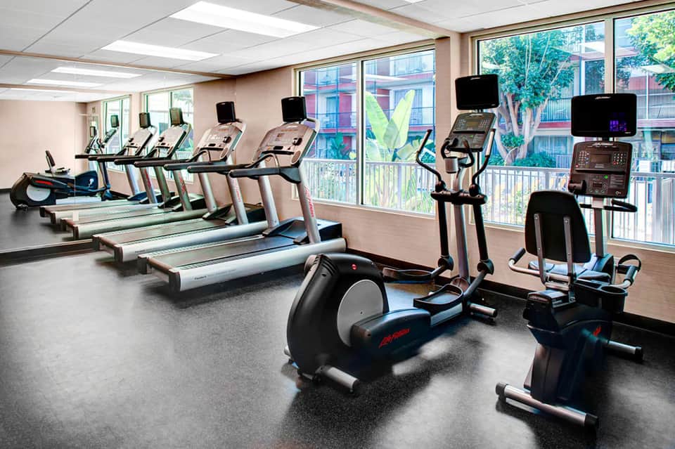 Fitness center with multiple treadmills, exercise bikes, and equipment near windows
