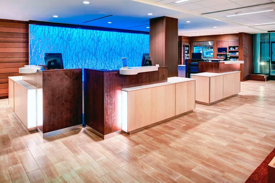 Modern hotel lobby with reception desks, dark wood finishes, and blue accent wall