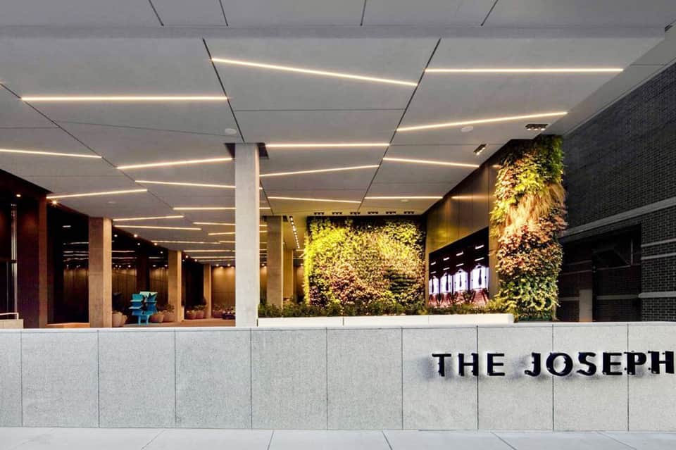 Modern hotel lobby with living green wall, geometric ceiling lights, and contemporary design