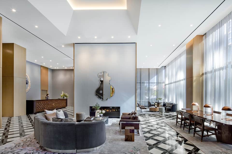 Luxury hotel lobby with curved sofa, fireplace, high ceilings, and modern décor