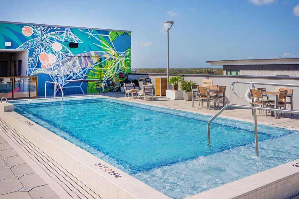Modern outdoor pool with vibrant mural wall, shallow splash area, and lounge seating