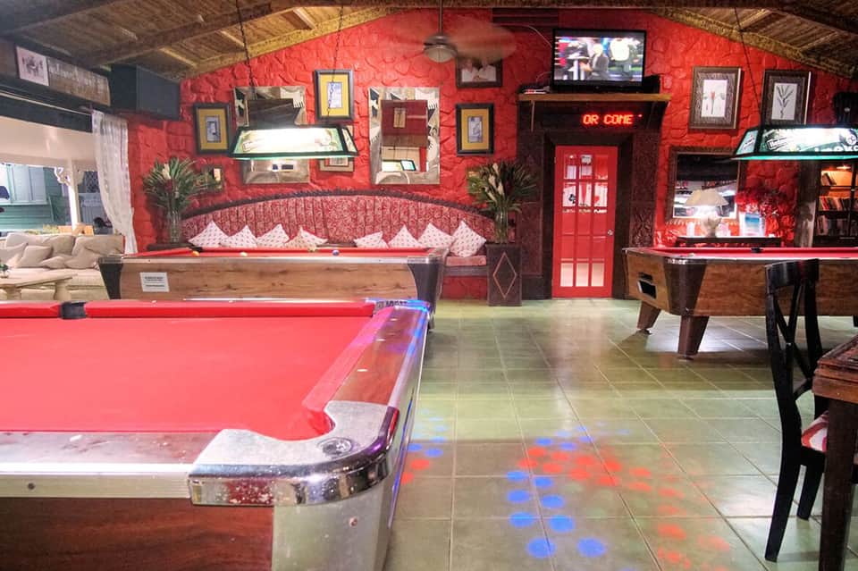 Colorful recreation room with red walls, billiards table, seating area, and entertainment setup