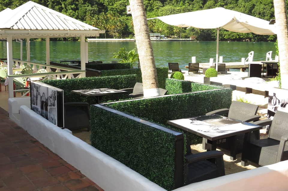Waterfront restaurant with covered pavilion, dining tables, and lush greenery