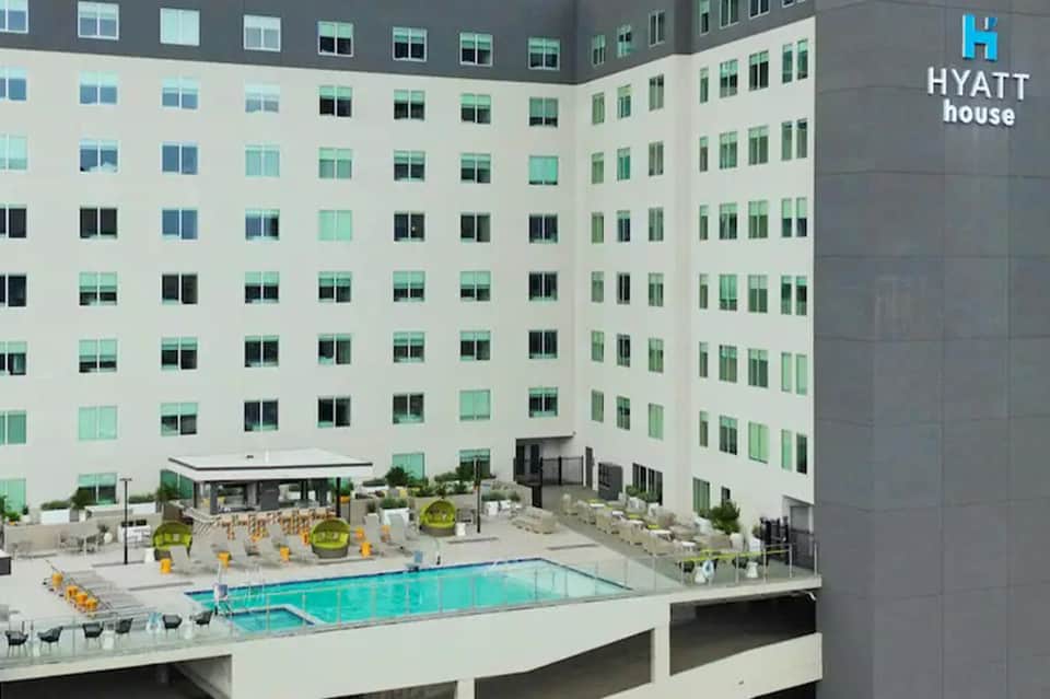 Aerial view of courtyard pool surrounded by Hyatt house building with yellow umbrellas and modern architecture