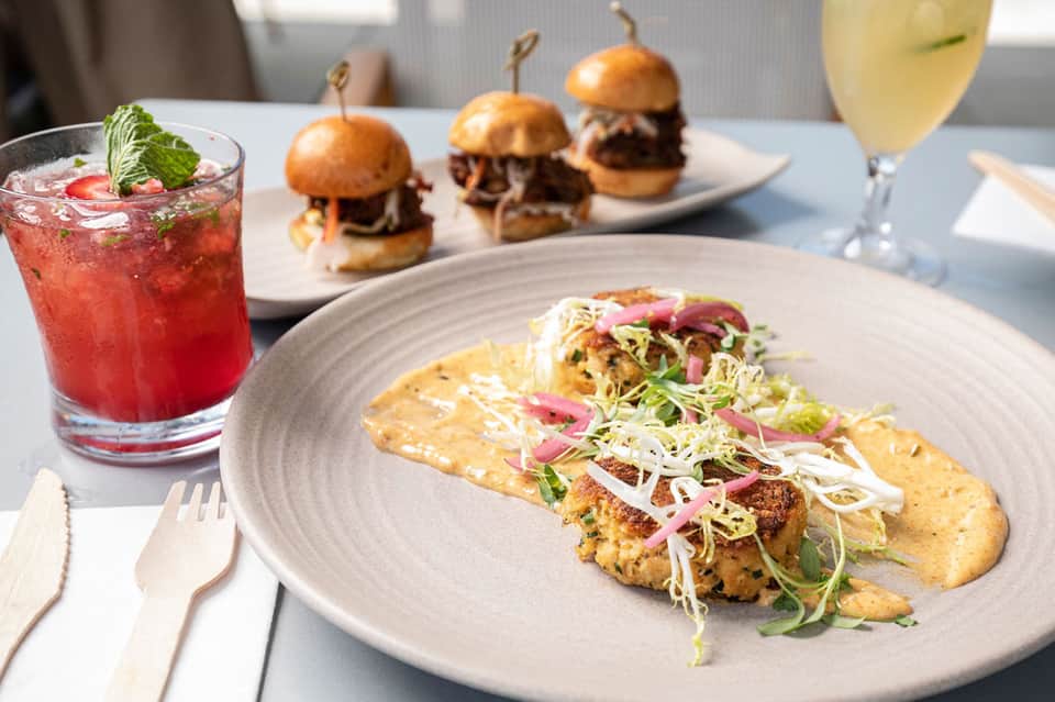 Gourmet dining plate with tacos, cocktails, and sliders on white table setting