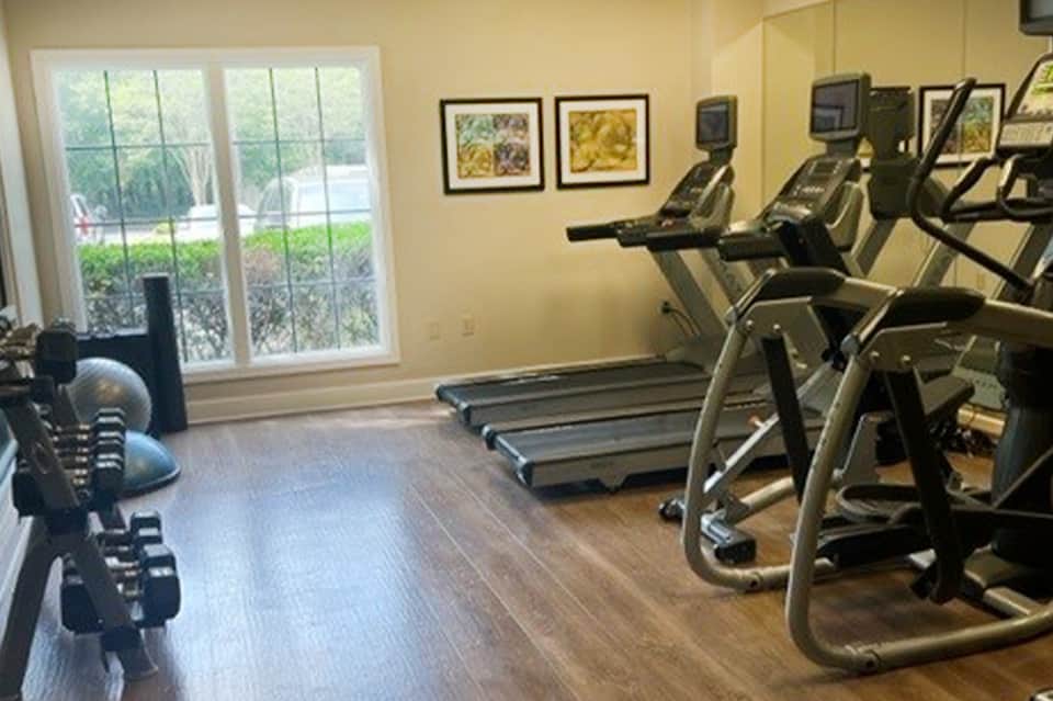 Modern fitness center with cardio equipment and large windows overlooking grounds