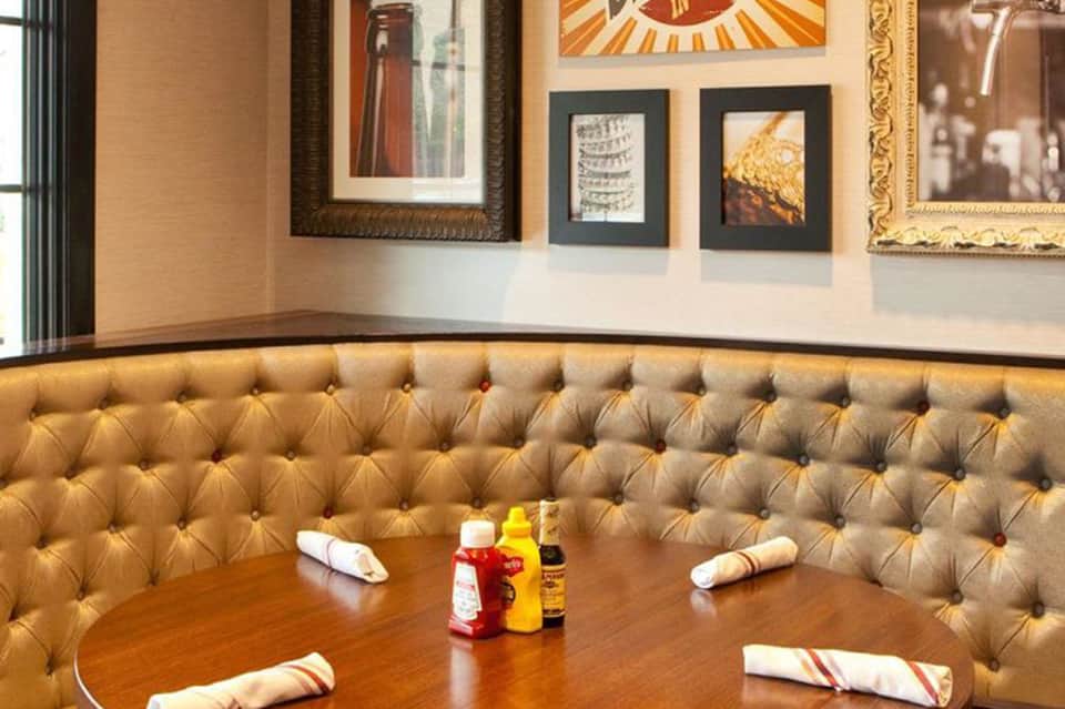 Fine dining restaurant with tufted gold booth seating, framed artwork, and place settings