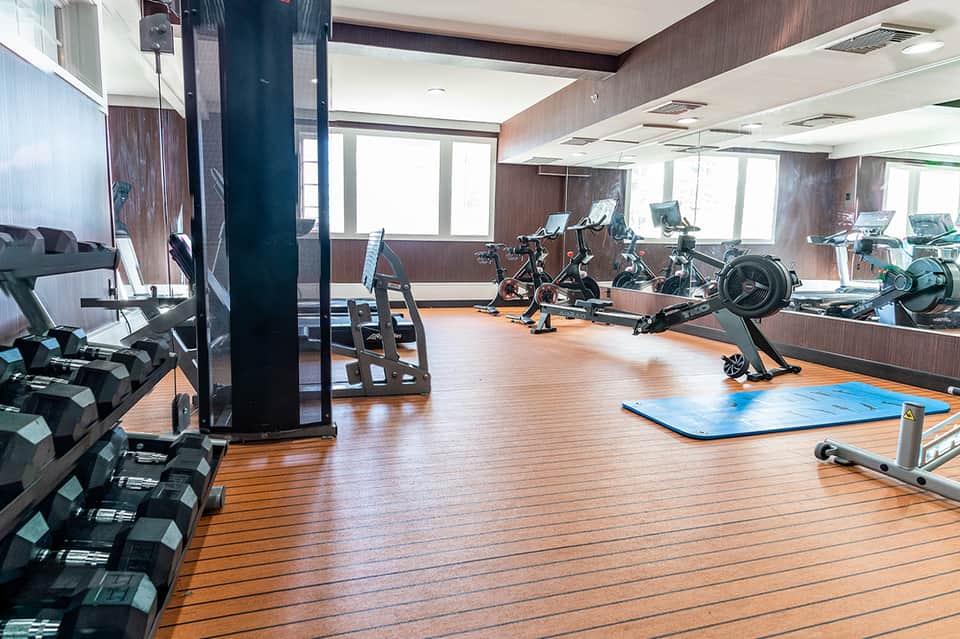 Fitness center with dumbbells, stationary bikes, and mirrors with wooden flooring and ocean views
