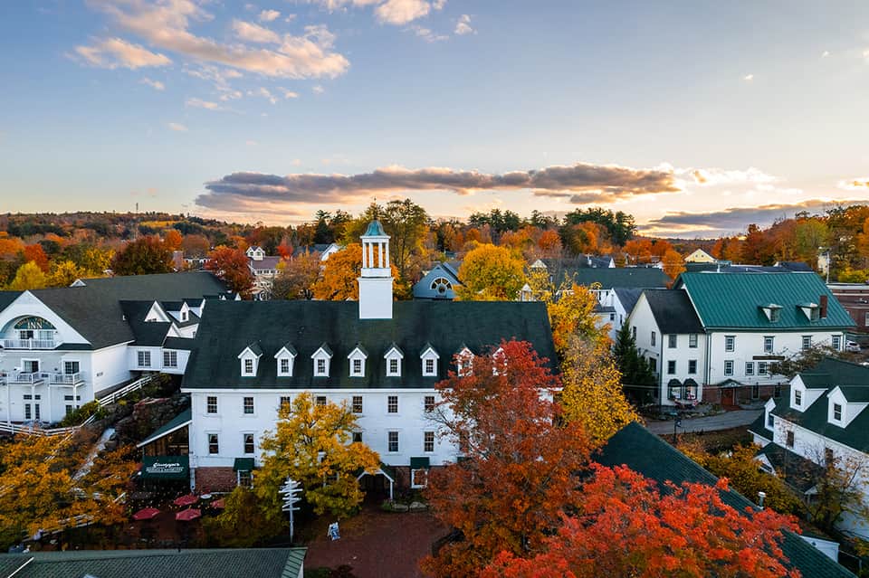 New England inn with white exterior, steeple, and fall foliage surrounding the building