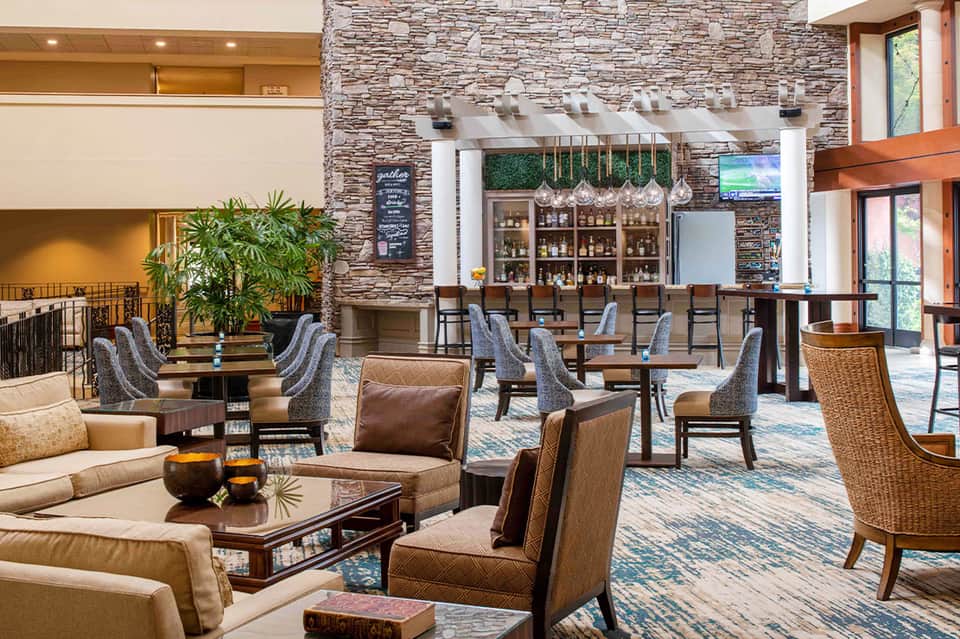 Contemporary resort lobby lounge with stone fireplace, bar area, comfortable seating, and two-story design