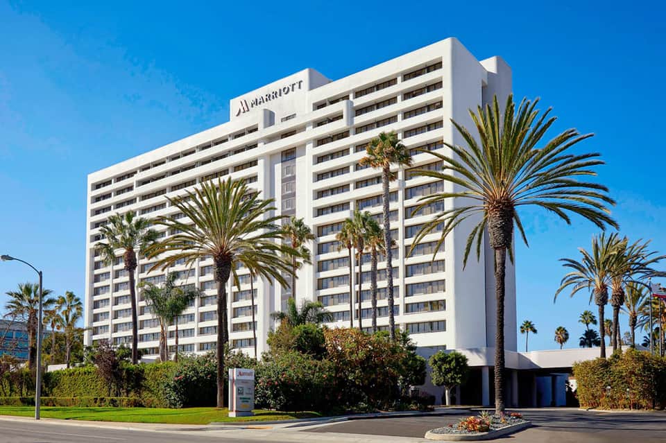 Marriott hotel exterior with white facade, palm trees, and clear blue sky