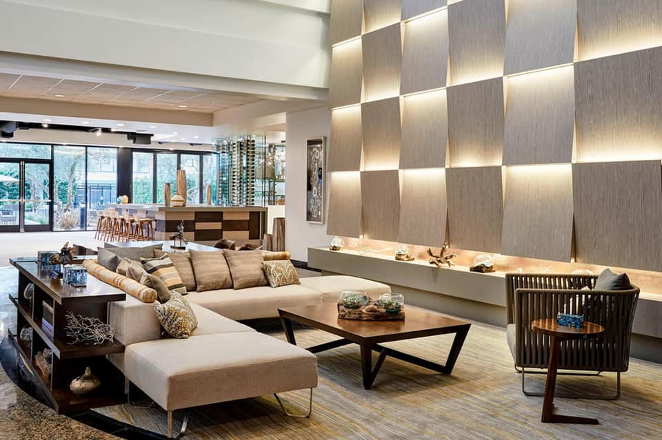 Contemporary hotel lobby lounge with geometric wall panels, modern furniture, and floor-to-ceiling windows