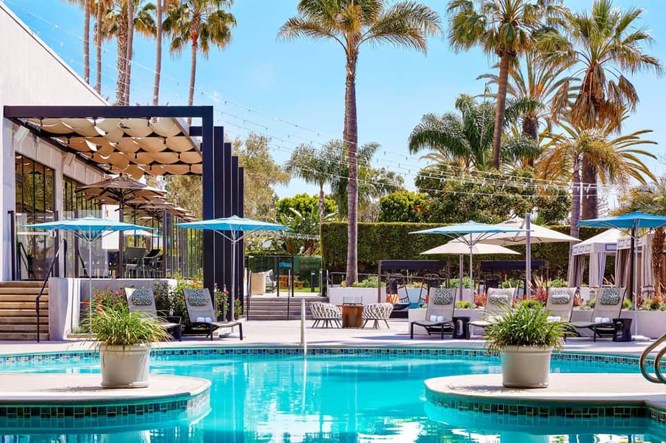 Resort pool area with pergolas, lounge chairs, and palm tree landscaping