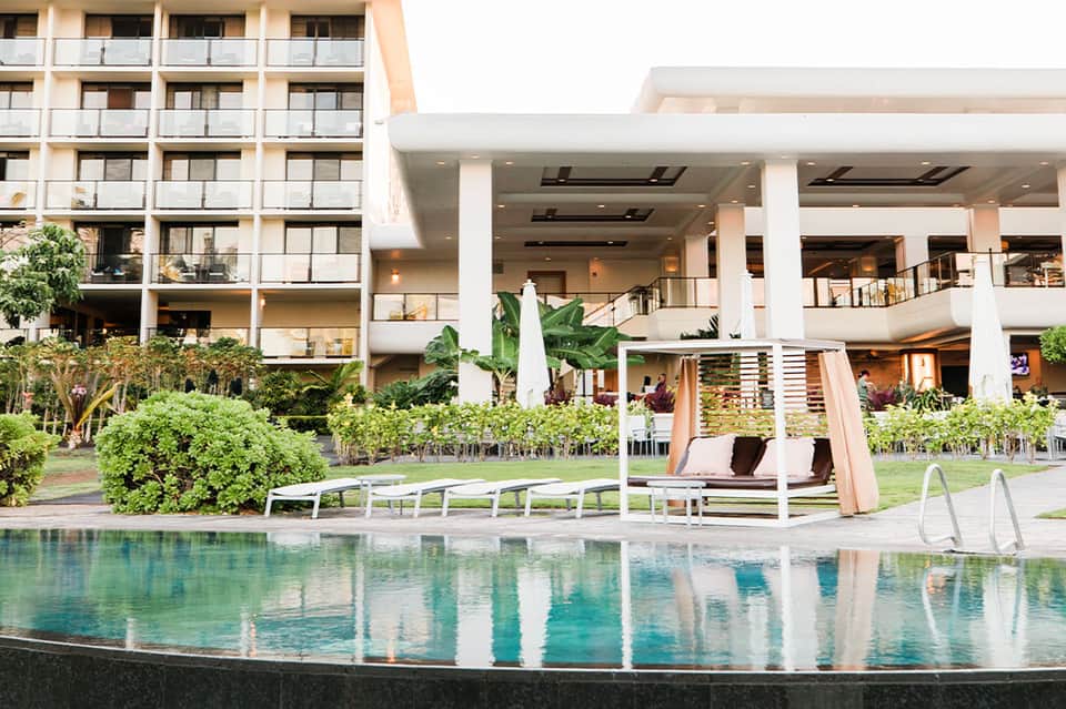 Modern resort pool with loungers and pergola adjacent to multi-story hotel building