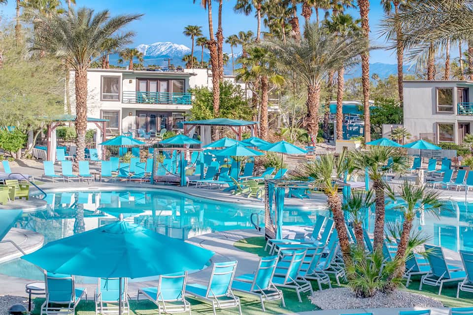 Large resort pool complex with turquoise umbrellas and palm trees
