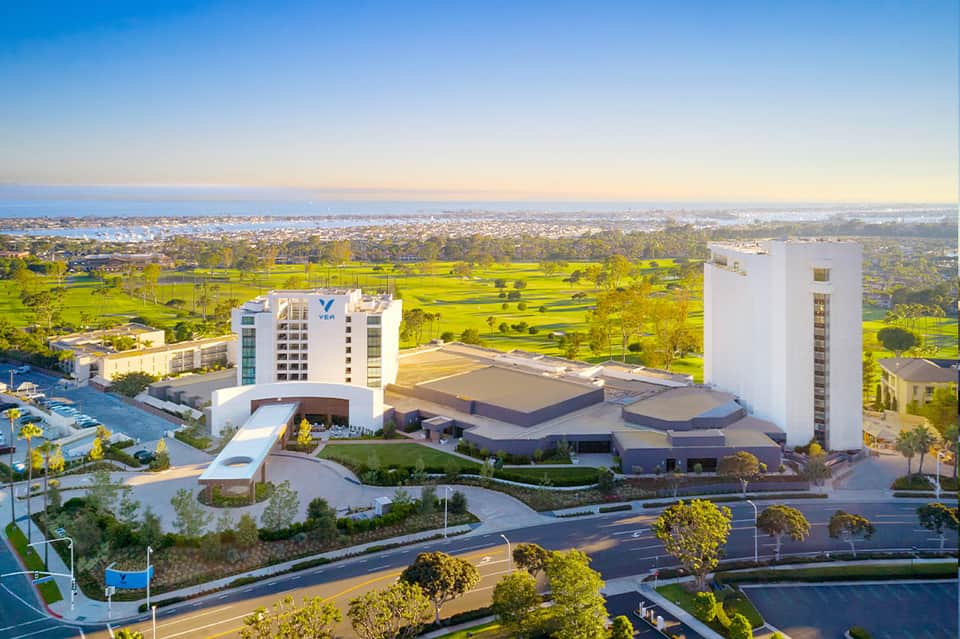 Modern resort complex with twin towers overlooking green landscape and bay