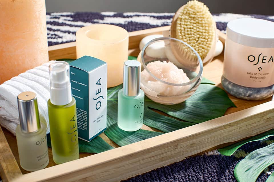 Spa products and body care items arranged on wooden tray with towels and brush