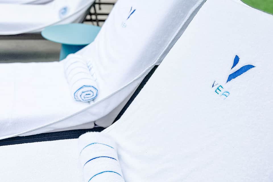 Close-up of folded white towels with blue spa resort logo embroidered on them