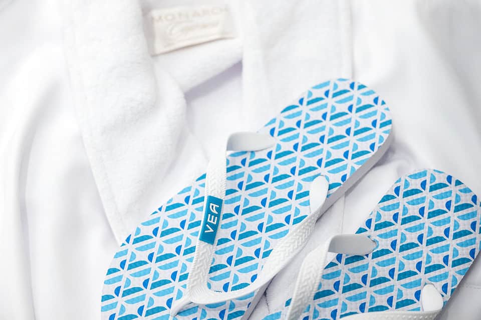 White bathroom slippers with blue geometric pattern on fluffy white towel
