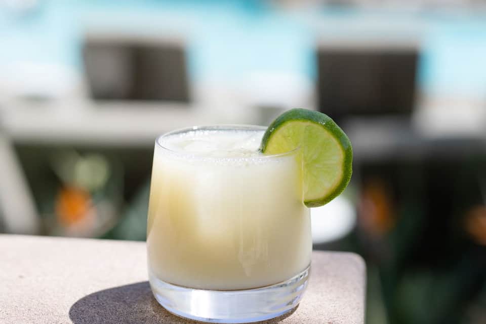 Margarita cocktail with lime wedge and salt rim on white poolside surface