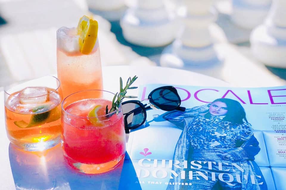 Colorful cocktails on beach magazine with sunglasses and coastal background