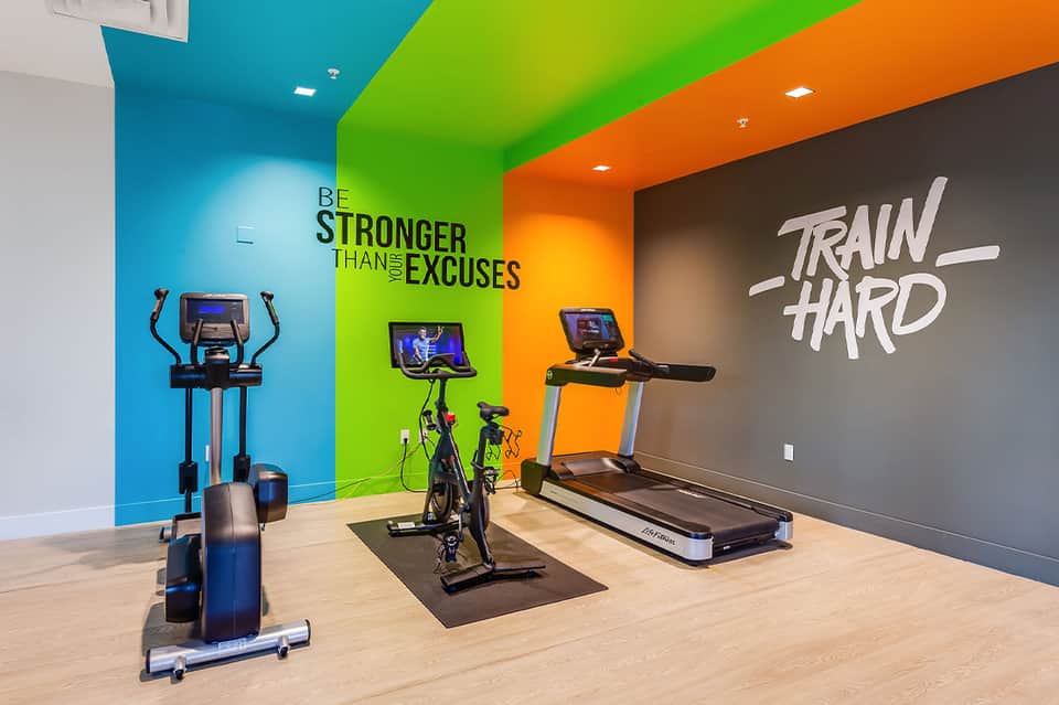 Modern fitness center with colorful accent walls, motivational signage, and exercise equipment