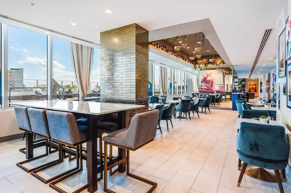 Modern high-rise lounge with floor-to-ceiling windows, contemporary seating, fireplace, and panoramic city views