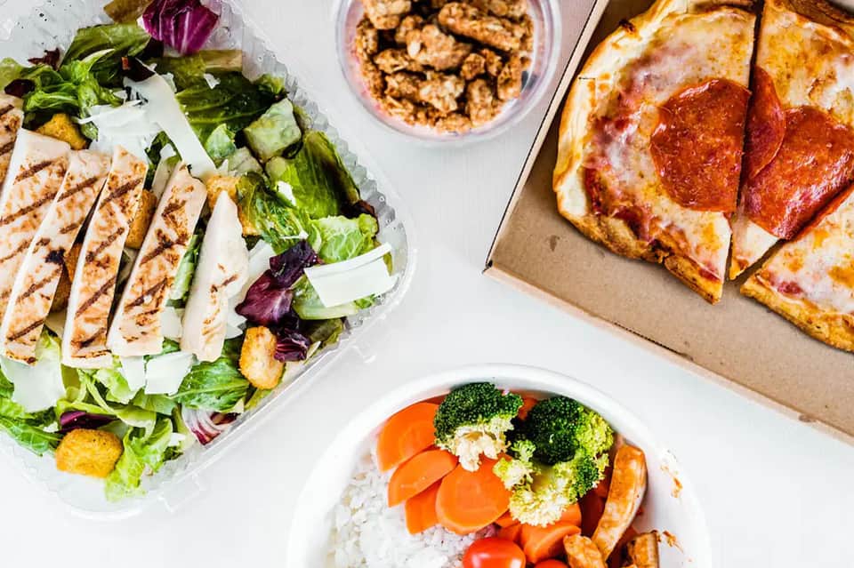 Resort dining spread featuring grilled chicken salad, pepperoni pizza, and vegetable rice dish