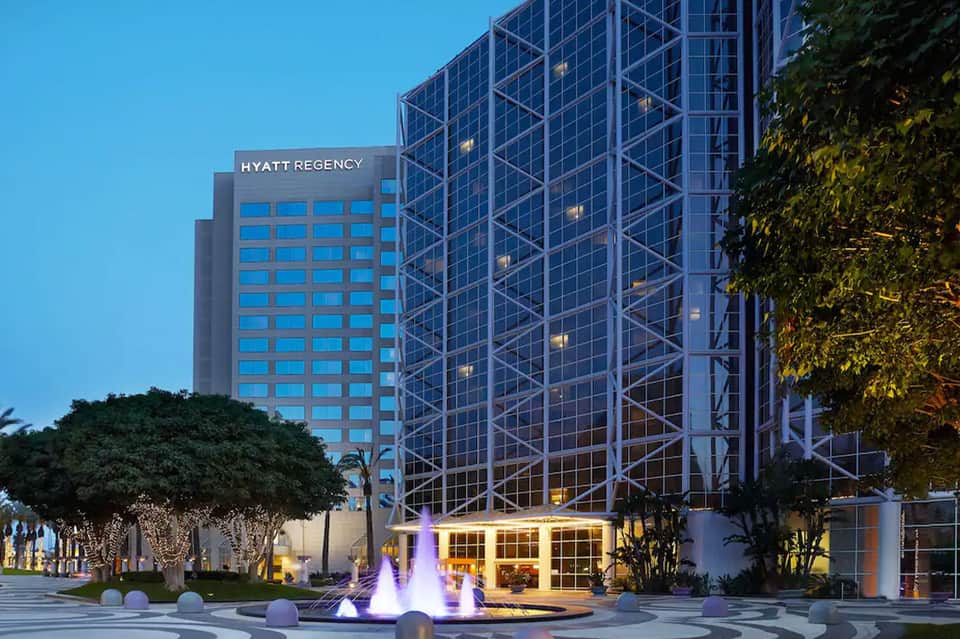 Modern Hyatt Regency hotel exterior at dusk with illuminated fountain and landscaping