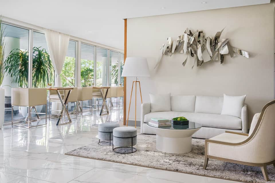 Modern living room with white sofa, wooden accents, floor-to-ceiling windows, and wall art