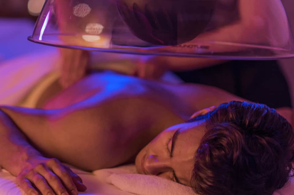 Person receiving spa treatment under purple and blue ambient lighting in wellness facility
