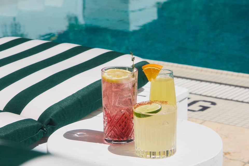 Colorful cocktails on poolside table next to striped lounge chair