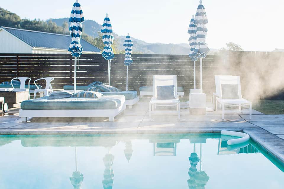 Modern pool with white loungers, blue striped umbrellas, and mountain views